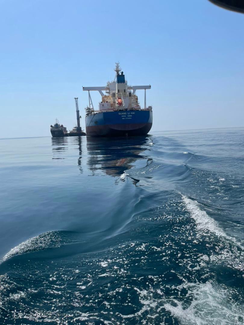 Bulk carrier at anchor, approached by launch